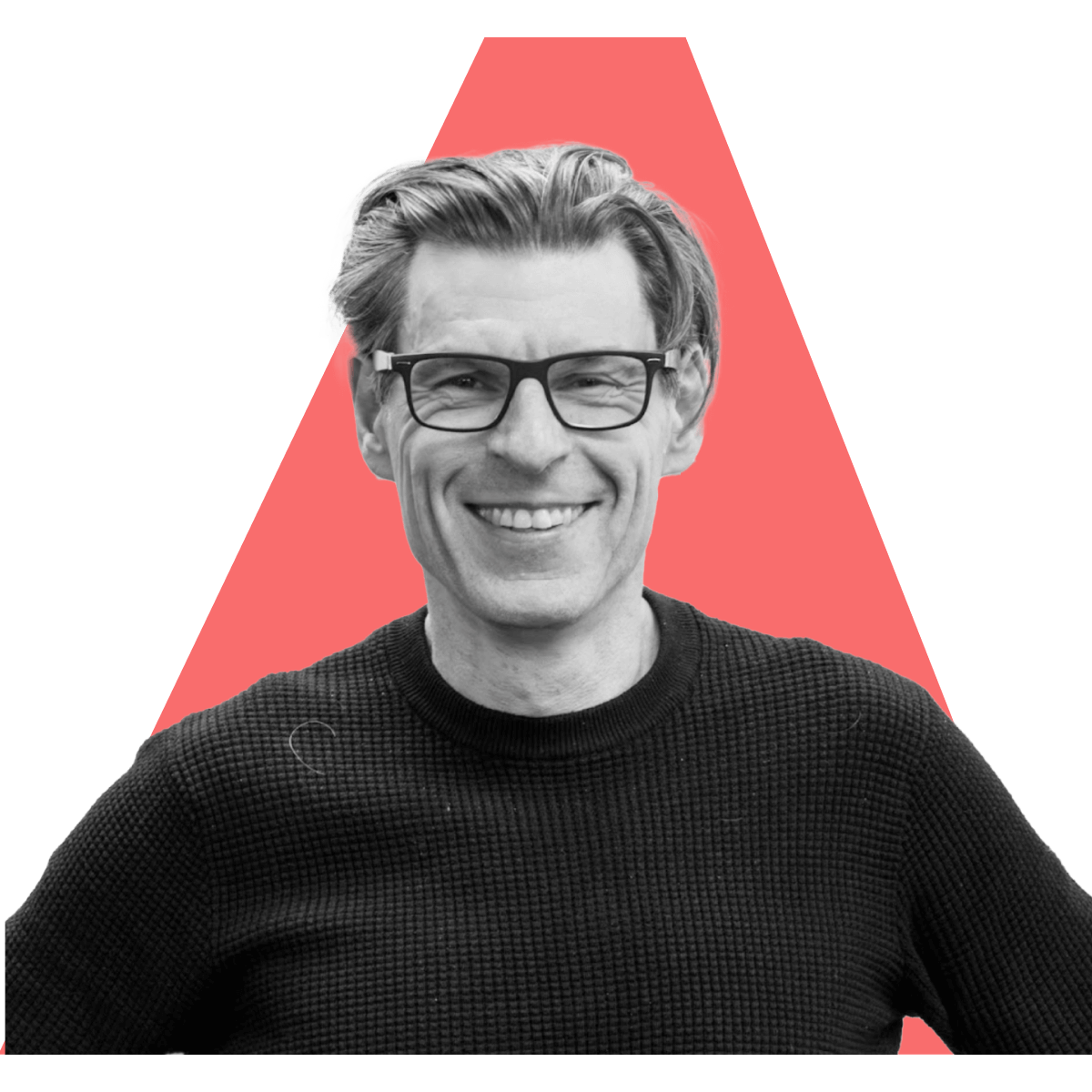 Black-and-white portrait of Tammer Kamel, smiling in glasses and a dark knit sweater, in front of the red Antler symbol